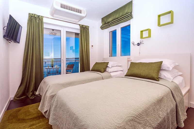 Chambre n°2 avec deux lits simples de 90 cm x 200 cm, balcon, climatisation et télévision.