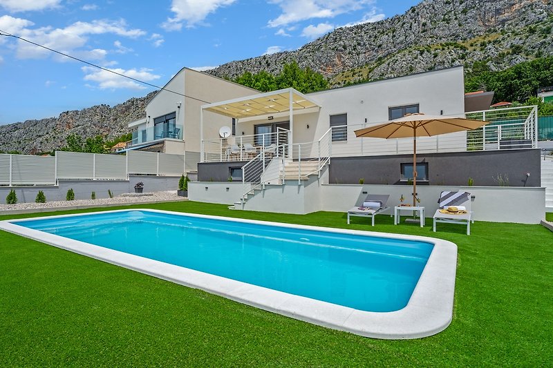 A private swimming pool 9m x 3,7m, a sun deck area with artificial grass and with 4 deck chairs, a lounge corner