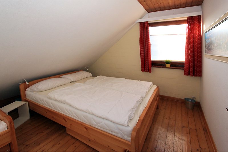 Schlafzimmer mit Doppelbett, Schrank, Nachttisch und Sessel