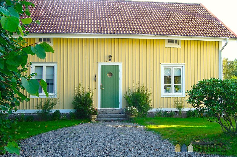 Gelbes Haus mit Sprossenfenstern und gepflegtem Garten.