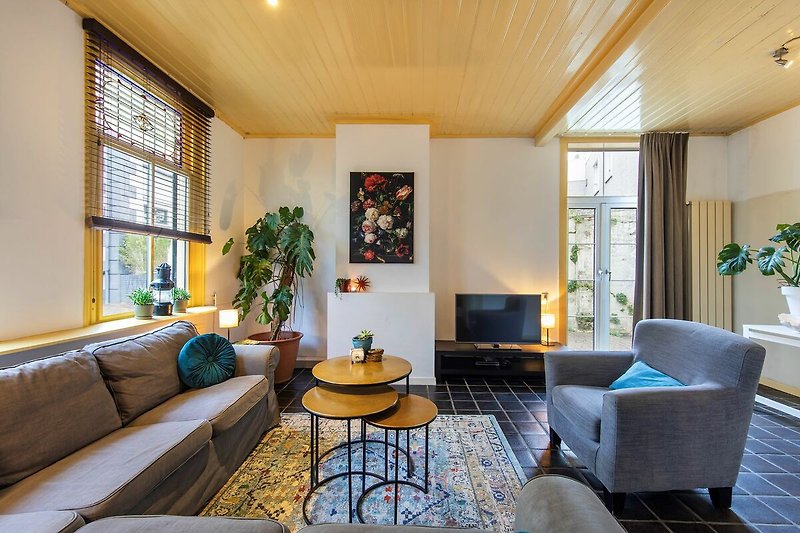 Modernes Wohnzimmer mit bequemer Couch, stilvollem Tisch, Pflanze und Fenster.