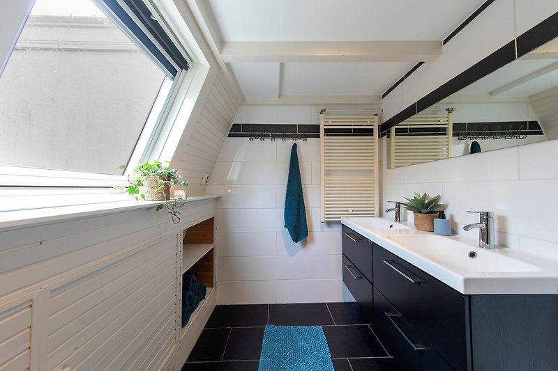 Modernes Badezimmer mit Spiegel, Waschbecken und Schränken.