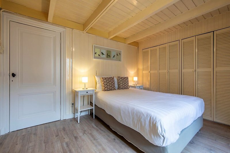 Modernes Schlafzimmer mit elegantem Bett, stilvoller Beleuchtung und Holzmöbeln.