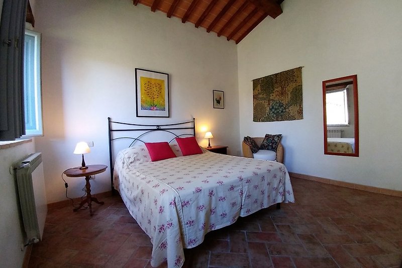 Schlafzimmer mit warmen Kastanienholzbalken und handgefertigten Deckenplatten