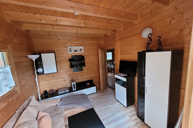 Gemütliches Wohnzimmer mit Holzbalken, Fenster und gemütlicher Couch.