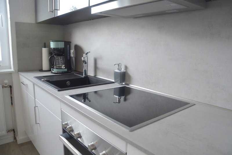 Moderne Küche mit grauen Schränken, Fenster und Gasherd.