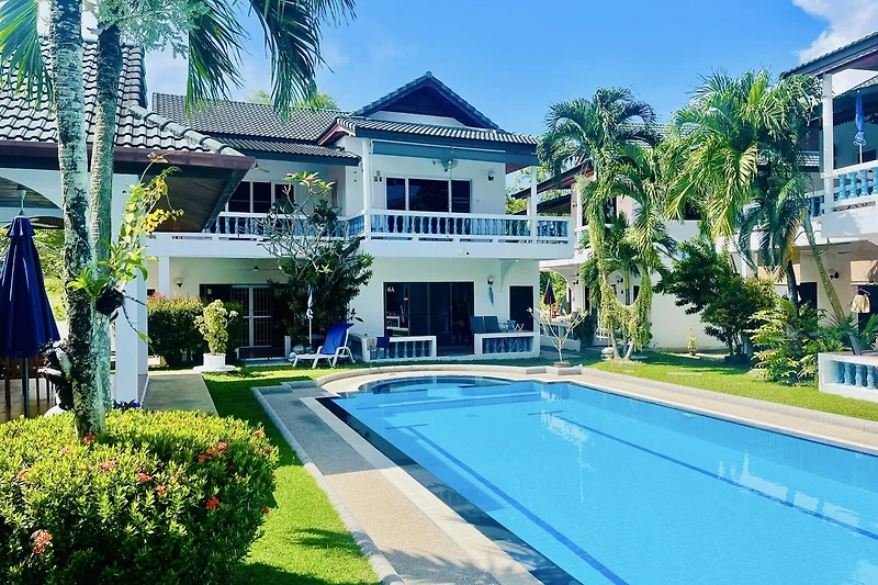 Luxuriöse Villa mit Pool, Palmen und Erholungsbereich.