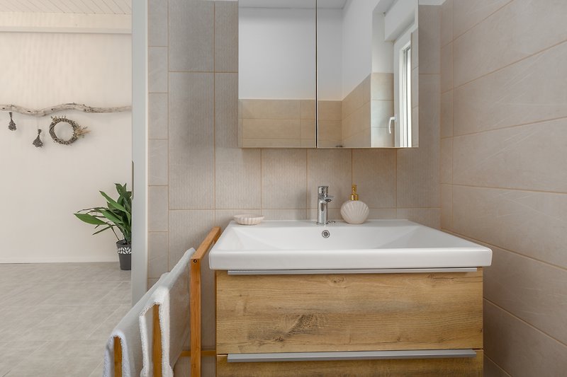 Gemütliches Badezimmer mit Spiegel, Waschbecken und Armatur.