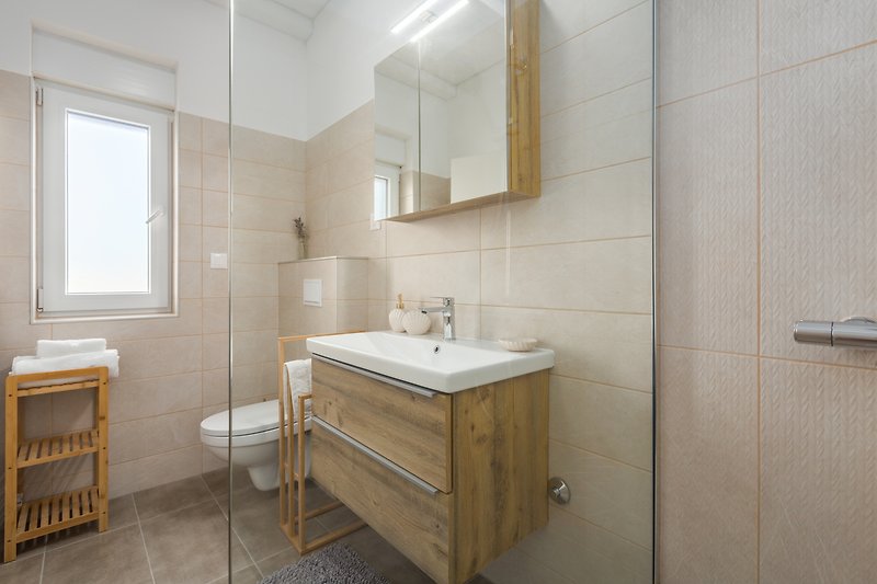 Badezimmer mit Spiegel, Waschbecken, Armatur und Badezimmerschrank.