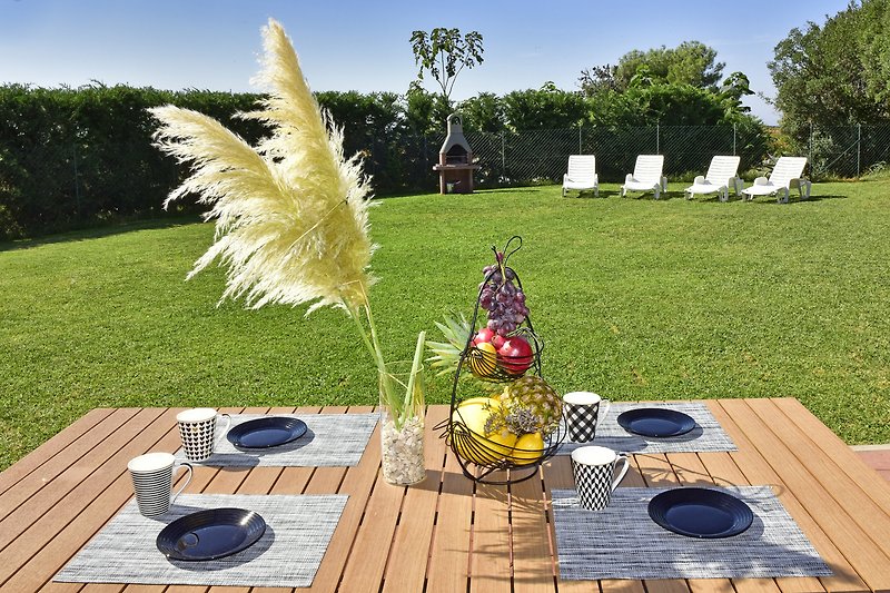 Garten mit Outdoor-Möbeln, Pflanzen und Tisch.