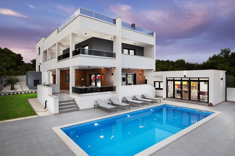 A modern property with a beautiful swimming pool and outdoor furniture.