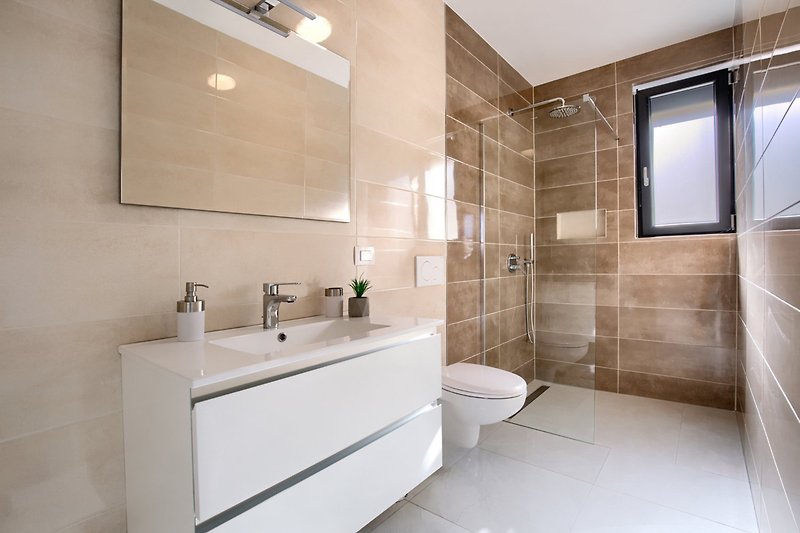 A modern bathroom with a sleek mirror, tap, and sink.