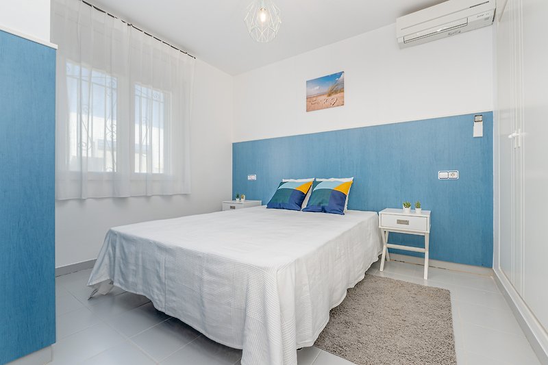 Moderne Wohnung mit stilvollem Interieur, bequemem Bett und blauer Dekoration.