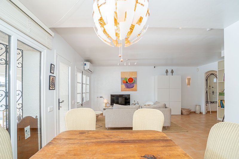 Stilvolles Wohnzimmer mit Holzmöbeln, gemütlichem Sessel und Deckenlampe.