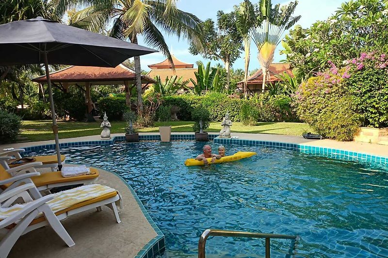 Schwimmbad mit Sonnenschirmen und Palmen - perfekte Erholung!