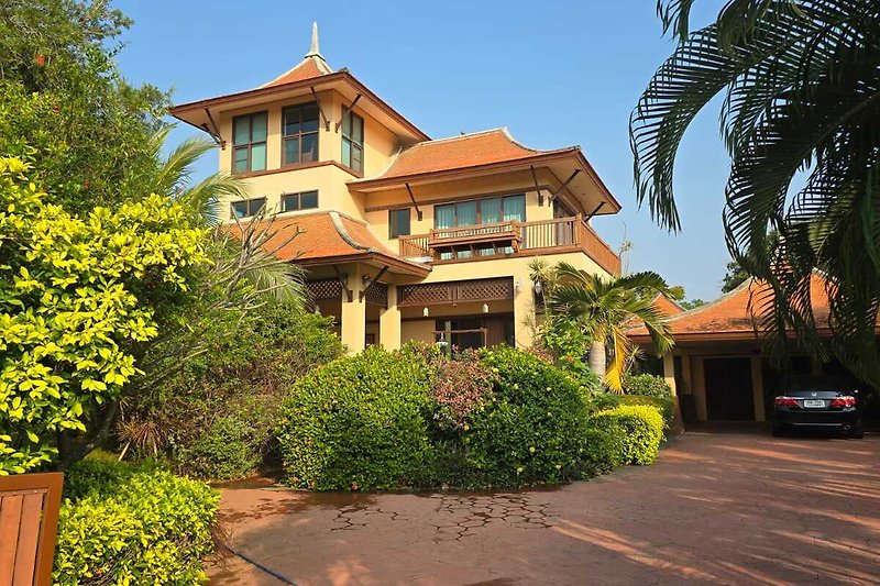 Große Pool Villa mit Palmen und Balkon, umgeben von schöner Landschaft.