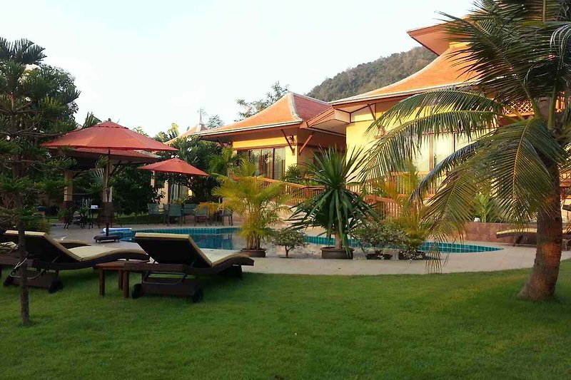 Luxuriöse Villa mit Pool, Sonnenliegen, Palmen und Garten.