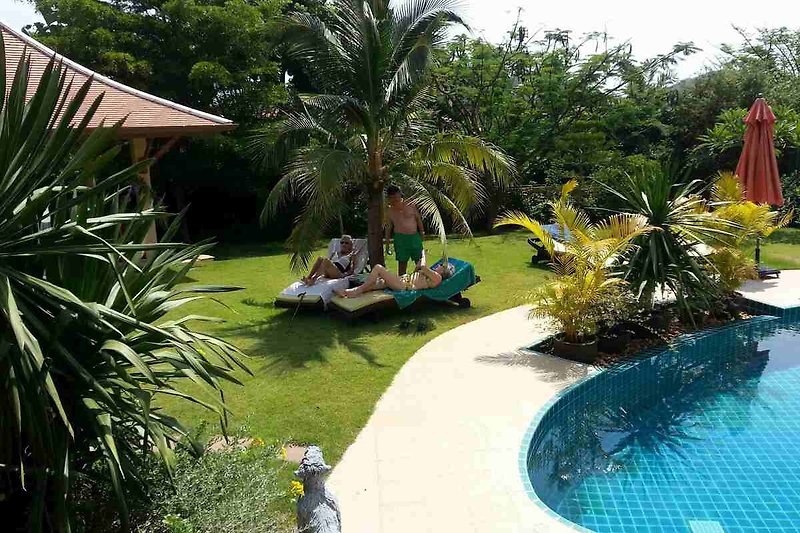 Schwimmbad mit Palmen, Liegestühlen und Sonnenschirmen.