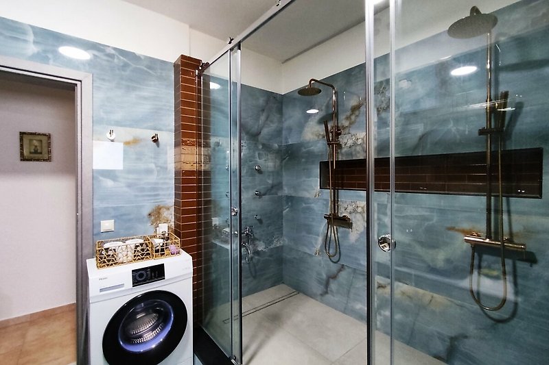 Moderne Badezimmerausstattung mit Dusche, Waschmaschine und Spiegel.