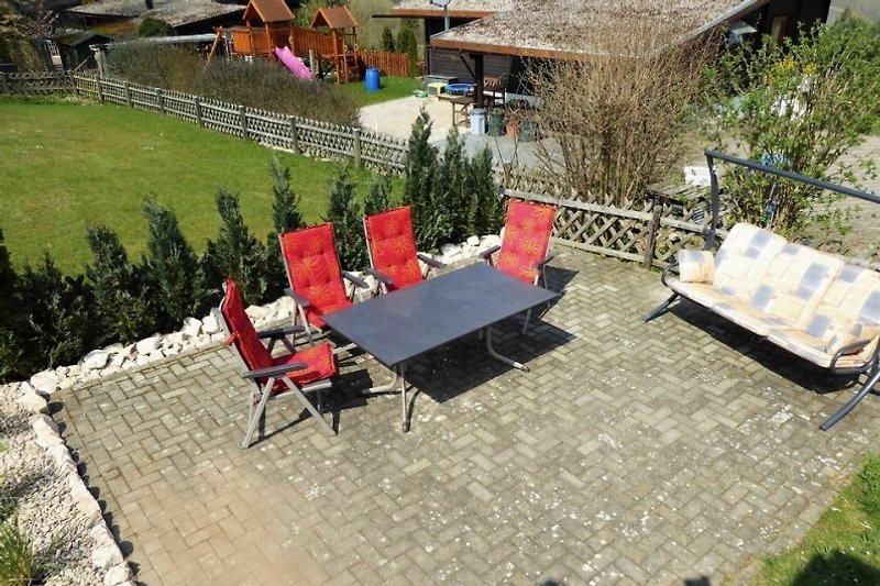 Die Sonnenterrasse mit großem Gartentisch und gemütlichen Stühlen.
