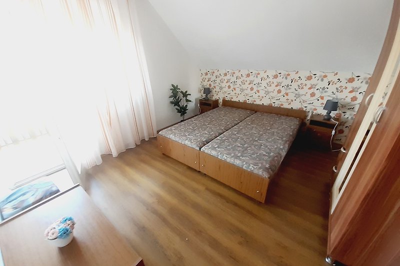Gemütliches Schlafzimmer mit stilvollem Holzbett und Fensterbehandlung.
