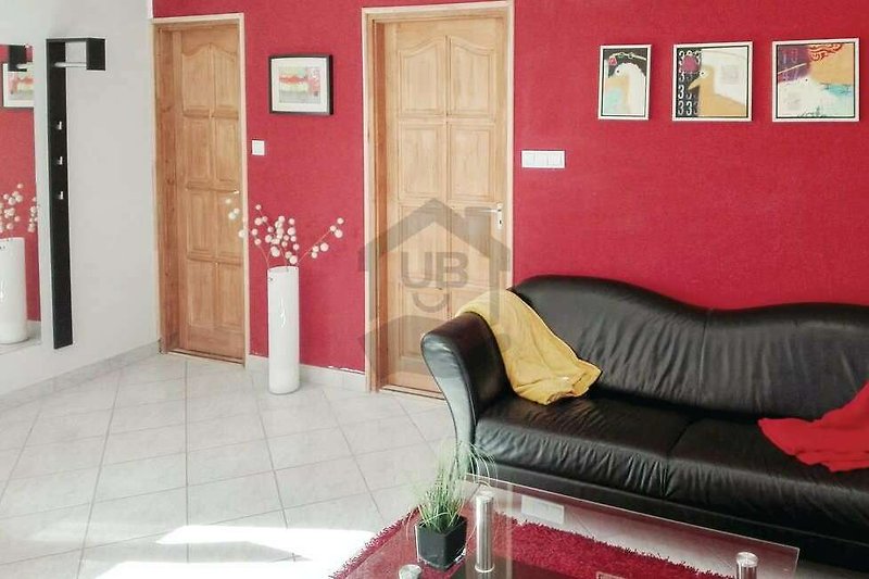 Gemütliches Wohnzimmer mit rotem Sofa, Holzboden und Kunst an der Wand.