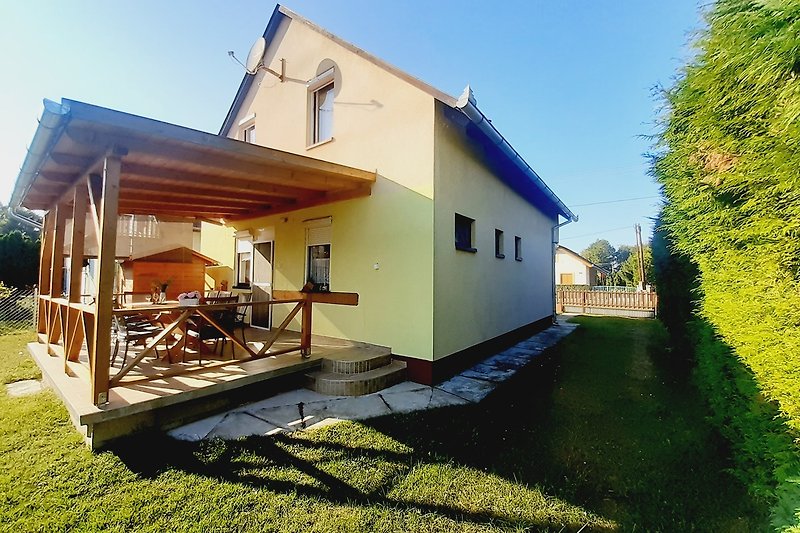 Schönes Haus mit Holzfassade, grünem Garten und malerischer Landschaft.