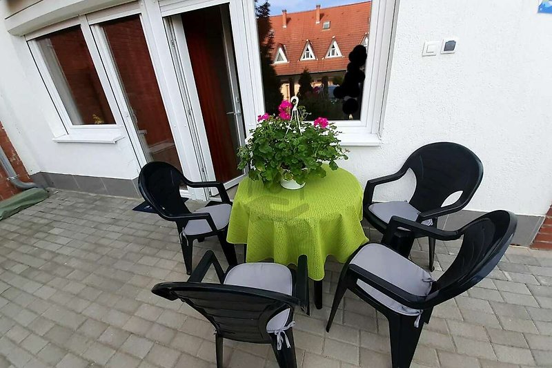 Schöne Terrasse mit Blumen, Holzmöbeln und Tisch im Freien.