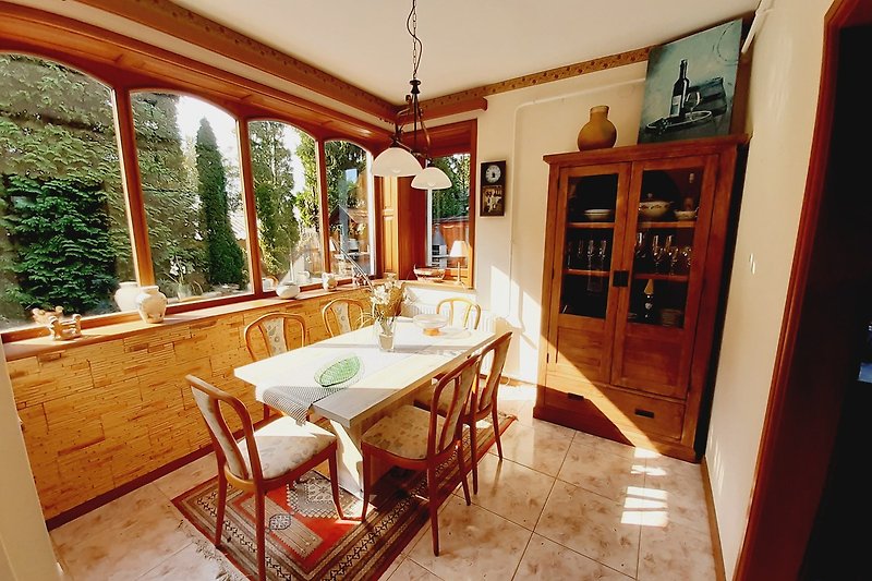 Küche mit Holzmöbeln, Fenster, Stühlen und Pflanzen.