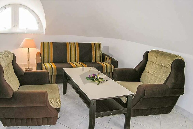 Gemütliches Wohnzimmer mit bequemer Couch, Tisch und Lampe.