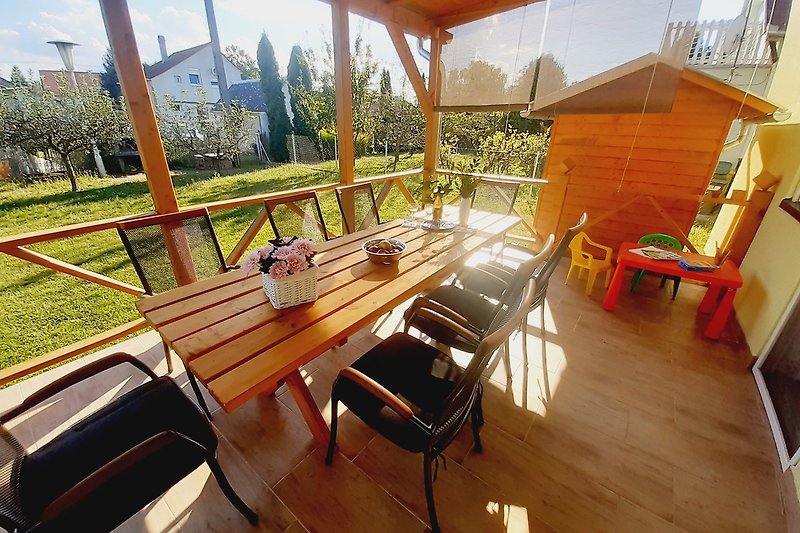 Haus mit Möbeln, Tisch und Stühlen auf der Terrasse.