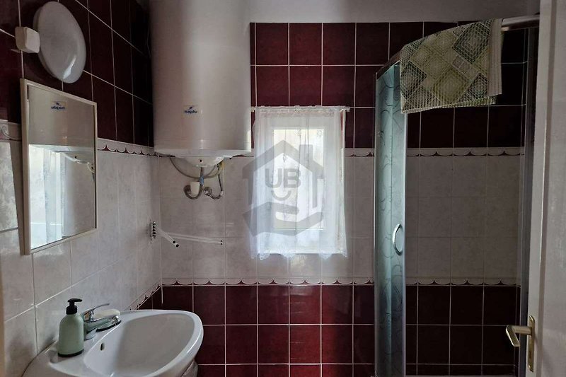 Badezimmer mit lila Waschbecken, Fenster und Fliesen.