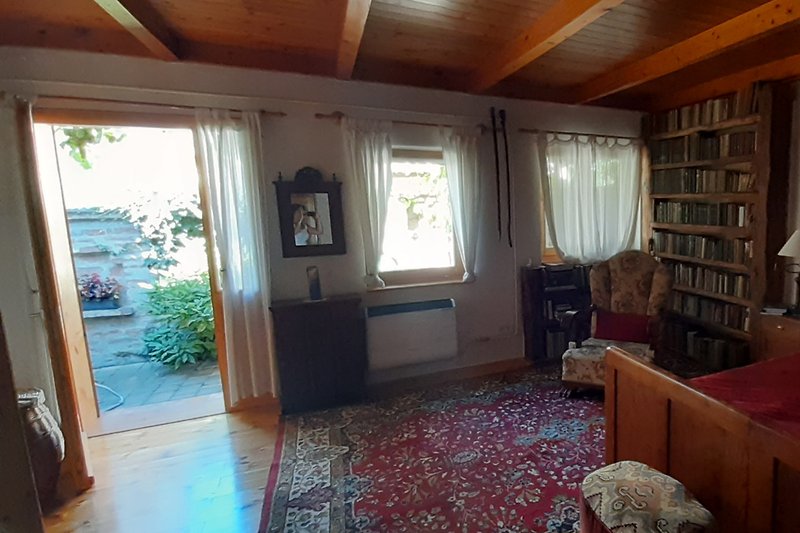 Wohnzimmer mit Holzmöbeln, Bücherregal und Fenster.