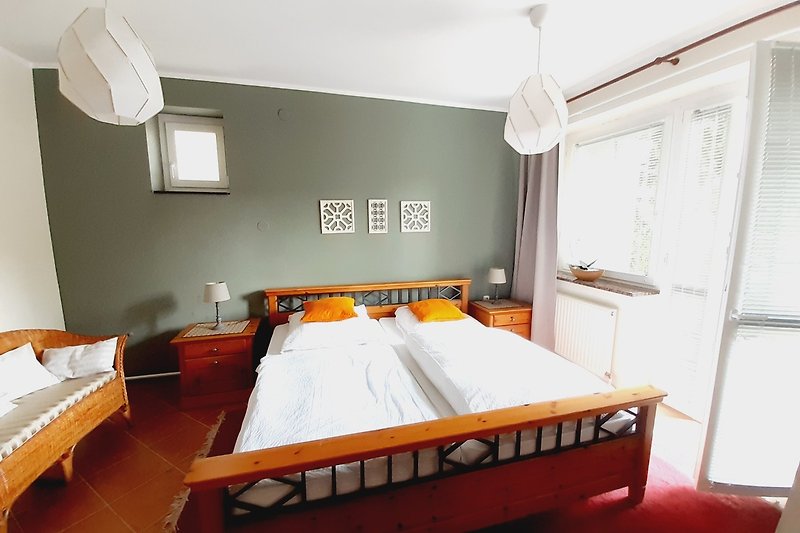 Schlafzimmer mit gemütlichem Bett, Fenster und Nachttisch.