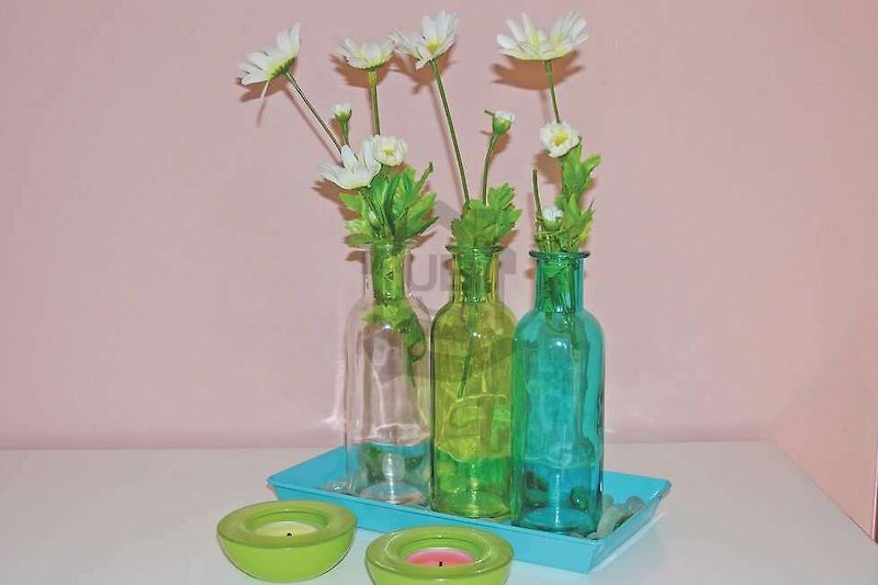 Schöne Blumenarrangements mit Glasflaschen und grünen Pflanzen.