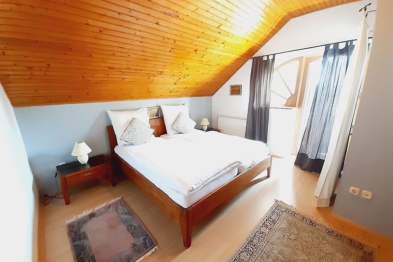 Stilvolles Schlafzimmer mit bequemem Bett, Kissen und Vorhängen.