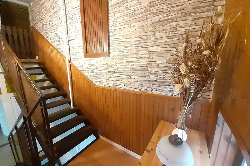 Gemütliches Zimmer mit stilvollem Holzboden und schöner Treppe.