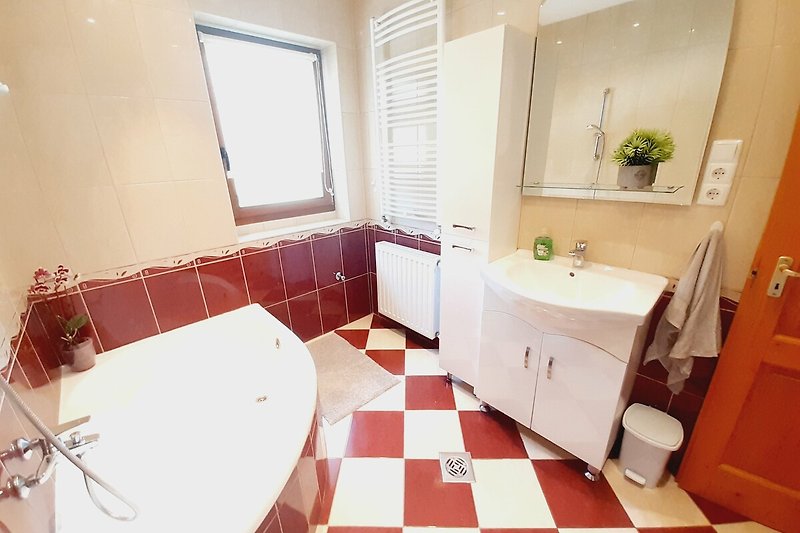 Schönes Badezimmer mit Spiegel, Waschbecken und Pflanze.