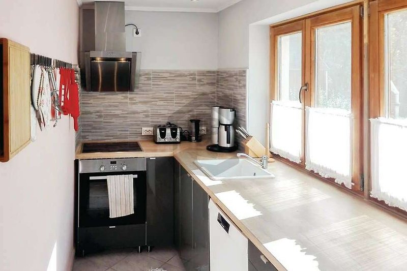 Moderne Küche mit Holzschränken, Arbeitsplatte und stilvoller Beleuchtung.