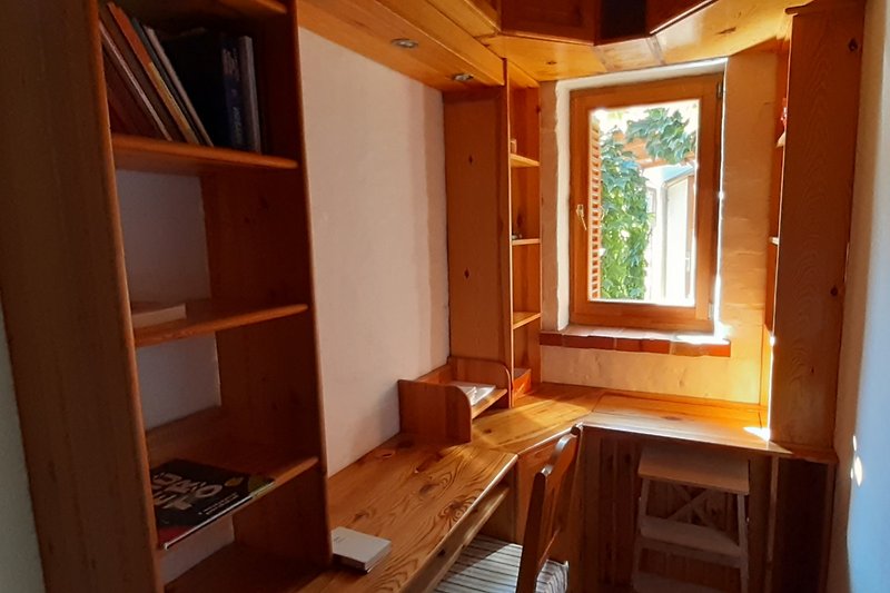 Wohnzimmer mit Holzmöbeln, Bücherregal und Tisch.
