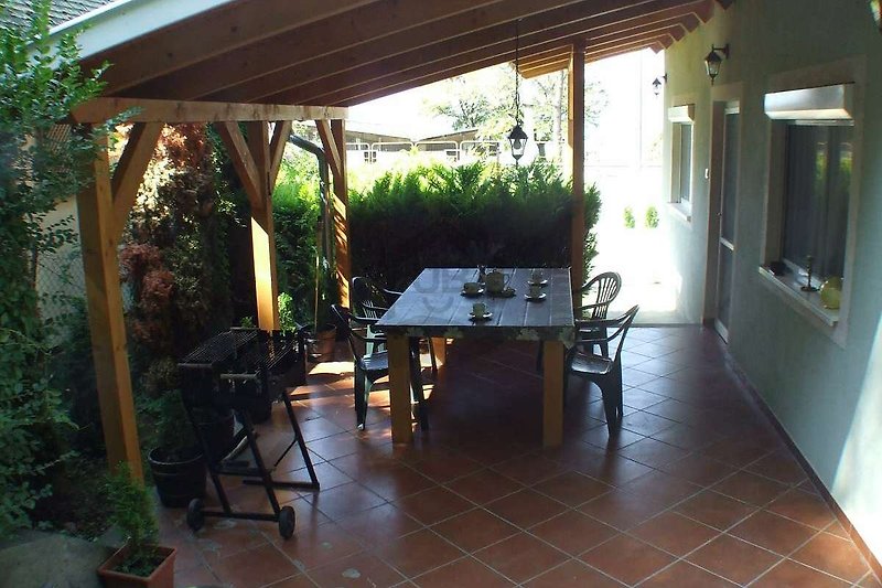 Schattiger Außenbereich mit Holzmöbeln und Pflanzen.
