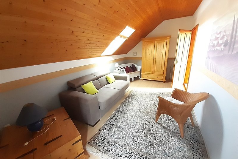 Wohnzimmer mit Holzmöbeln, bequemer Couch, Lampe und Pflanzen.