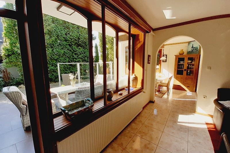 Wohnzimmer mit Holzmöbeln, Pflanzen und Fenster.