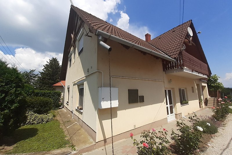 Charmantes Landhaus mit blühenden Pflanzen und malerischem Himmel.