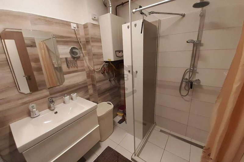 Badezimmer mit Spiegel, Waschbecken, Dusche und Armaturen.