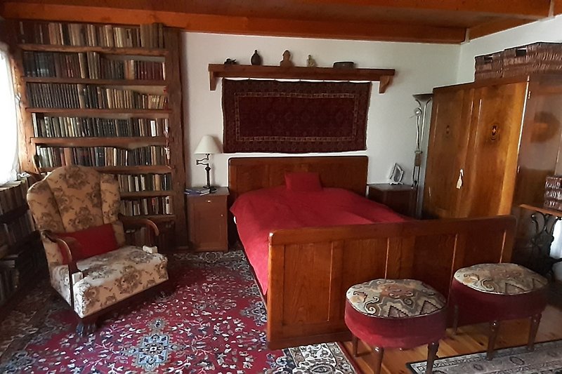 Wohnzimmer mit Holzmöbeln, Bücherregal und gemütlichem Sessel.