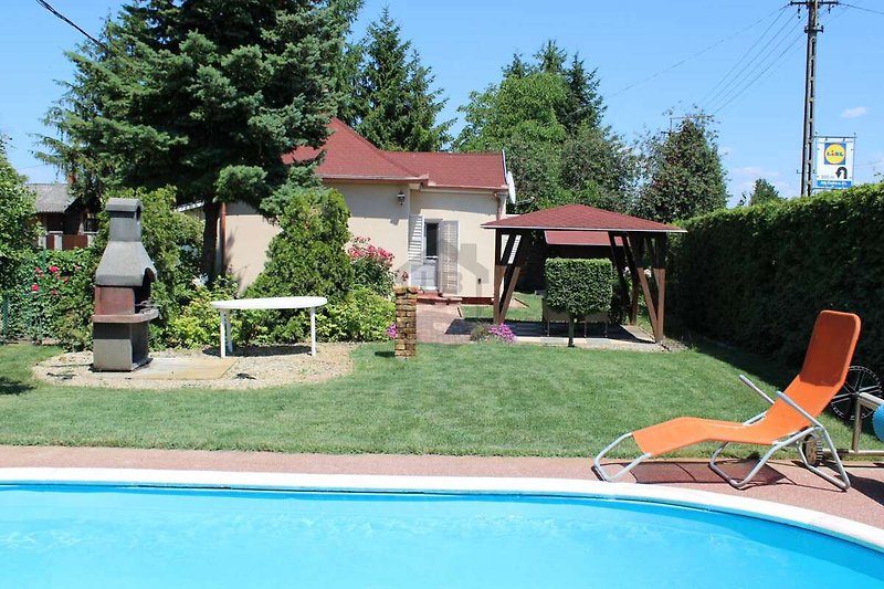 Schwimmbad, Gartenmöbel und Sonnenschirm in einem Ferienhaus.