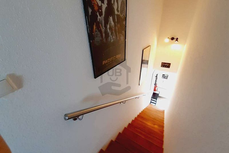 Schöne Holztreppe mit Kunst an der Wand und stilvollem Handlauf. Perfekt für einen erholsamen Urlaub.