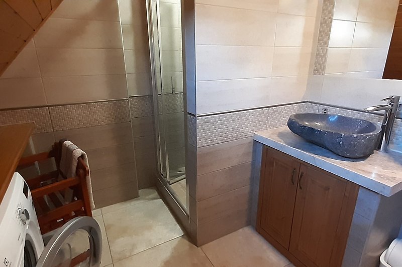 Modernes Badezimmer mit Glasdusche und Holzbadezimmerschrank.