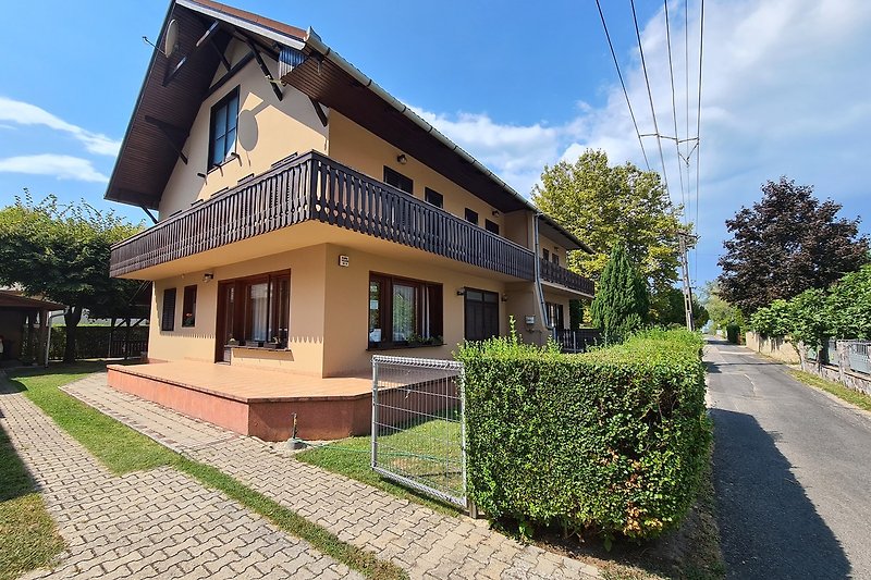 Charmantes Haus mit Garten, Bäumen und blühenden Sträuchern.